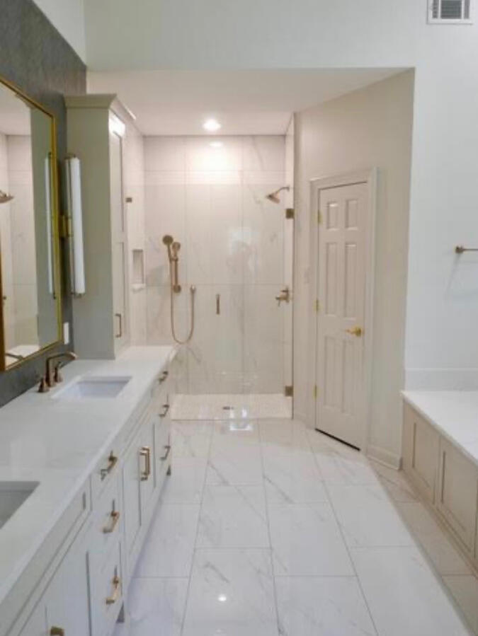 This complete remodel features stunning marble-look tile throughout the shower and flooring, creating a seamless and luxurious foundation for the space. An extra-long custom double vanity is flanked with abundant storage, balancing beauty with everyday pra